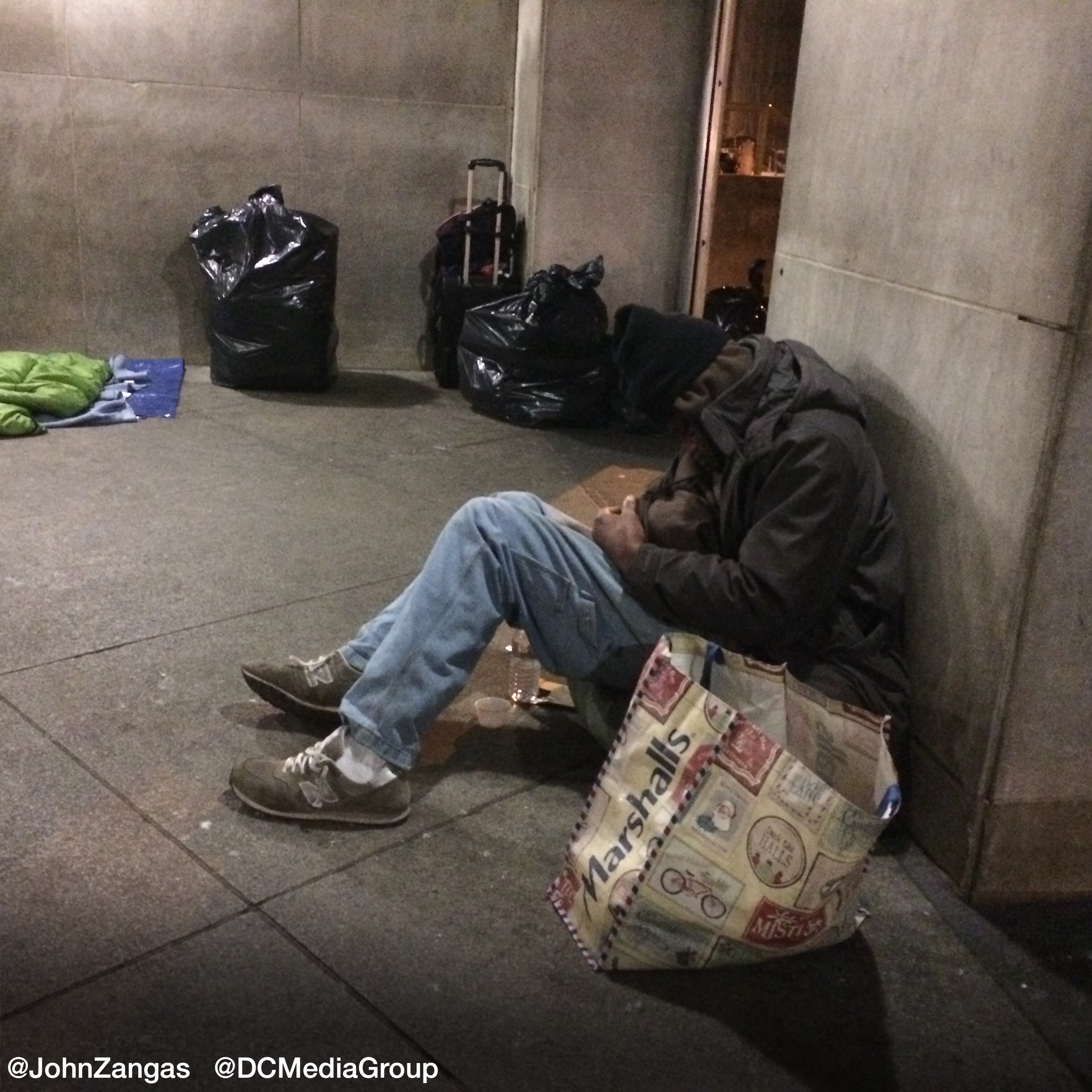 A man sits huddled on a sidewalk in downtown Washington, D.C..