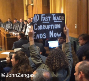 Mackenzie holds up a protest sign during a Senate Finance Committee hearing to consider Fast Track legislation.