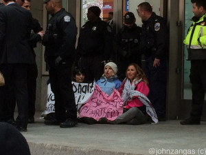 Three protesters affiliated with Code Pink break through police lines and block Convention Center doors./Photo by John Zangas
