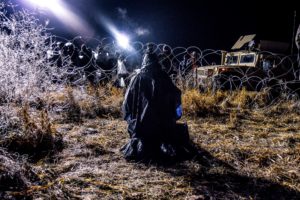 Water Protector prays covered with ice from water cannon./Photo by Rob Wilson